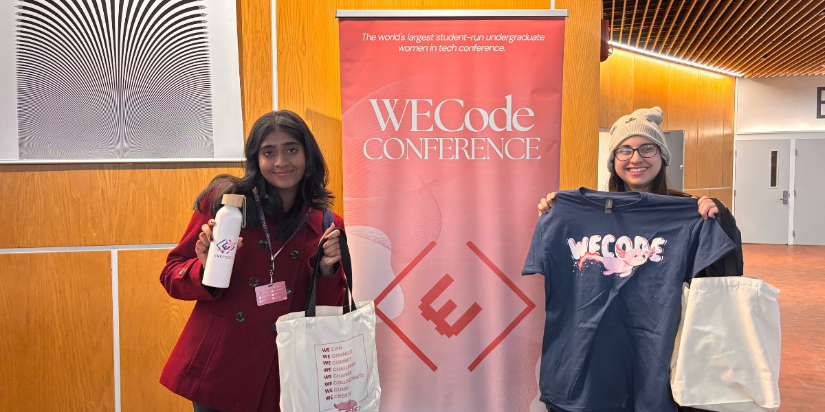 Two students posing with merchandise at the WECode Conference