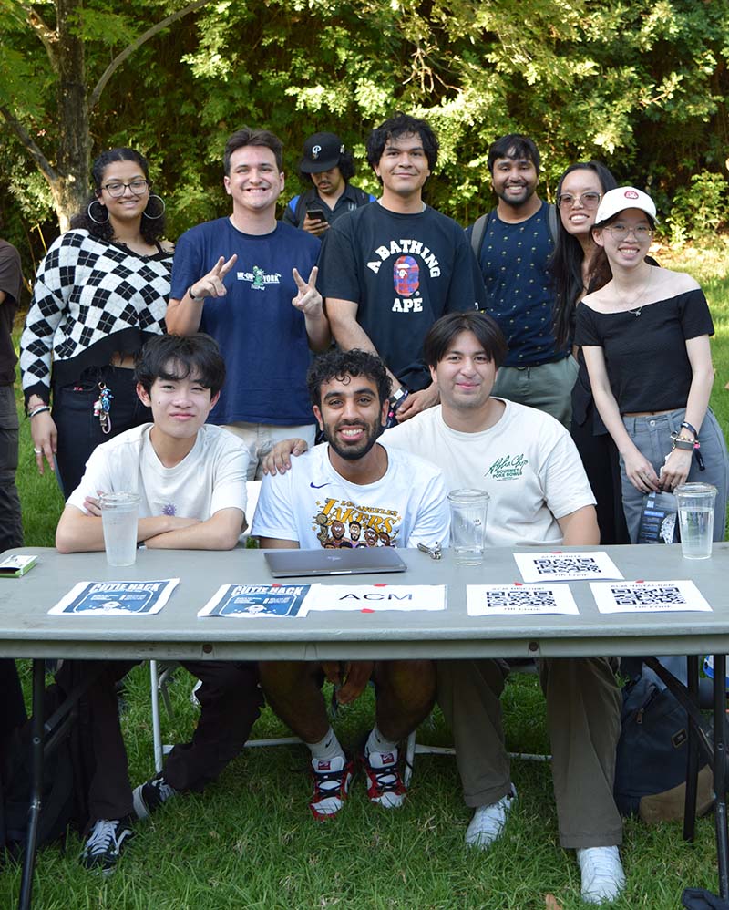 men and women members of ACM casually dressed posing outdoor in a grassy area 
