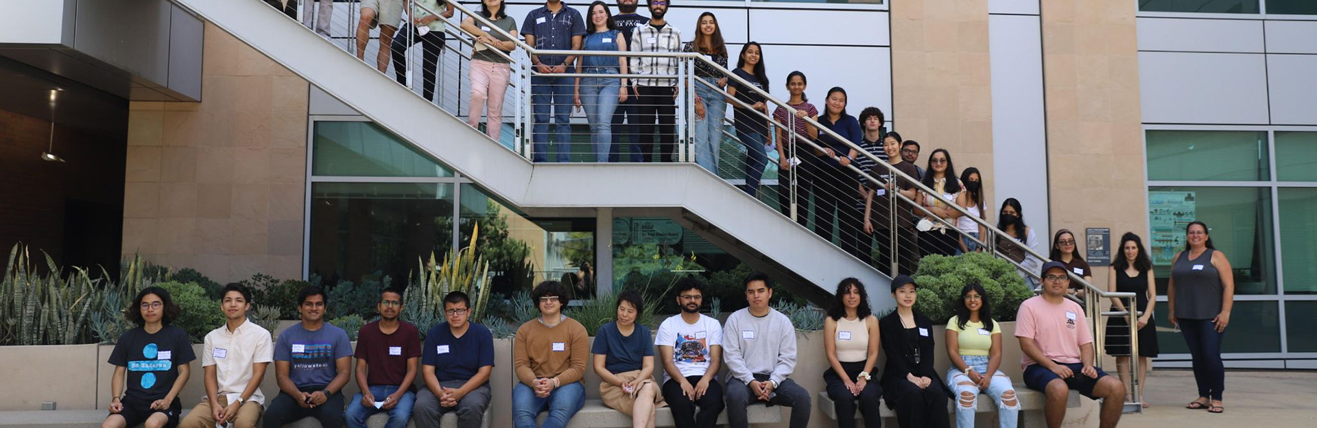 Photo of a group of roughly 3-4 dozen data science students posing for a group photo in a courtyard stairwell