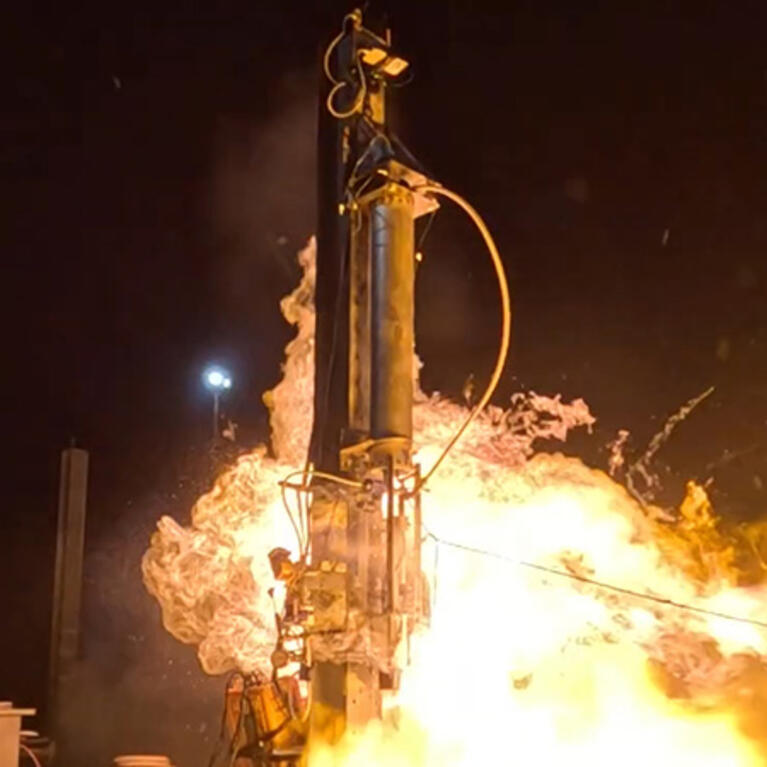 Photo showing the nightime launch of a rocket with flames surrounding the rocket.