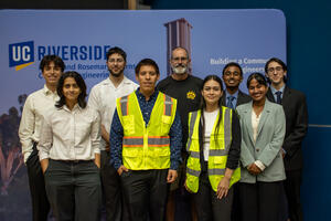A group of UCR engineering students and a faculty member pose together following a student project presentation, with two students wearing high-visibility safety vests.