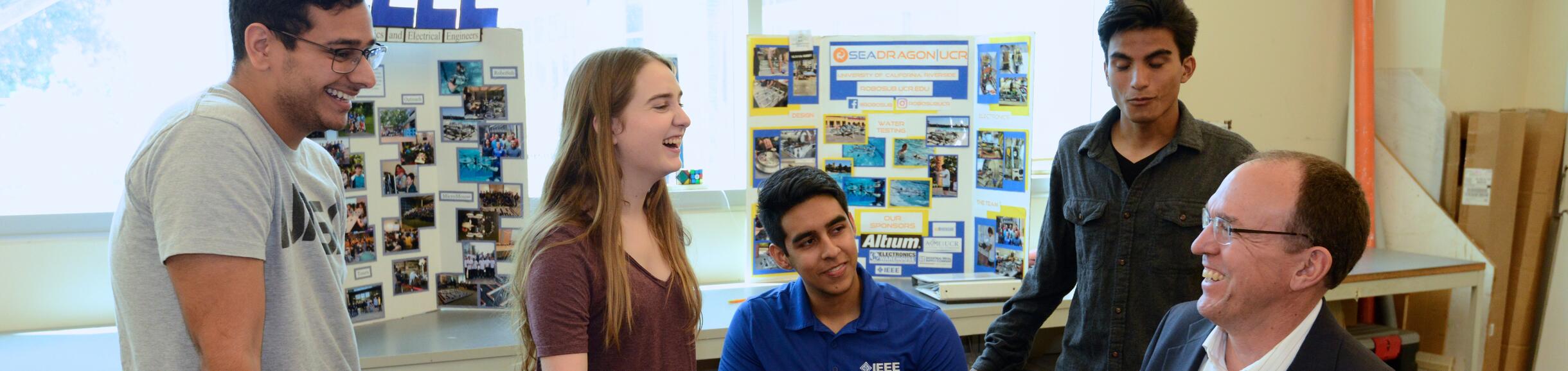 Dean Lynch and three engineering students smiling and gathered around a project