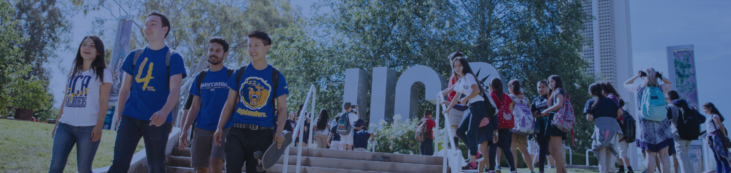 Students walking across the UC Riverside campus near the UCR landmark sign and gathering area.