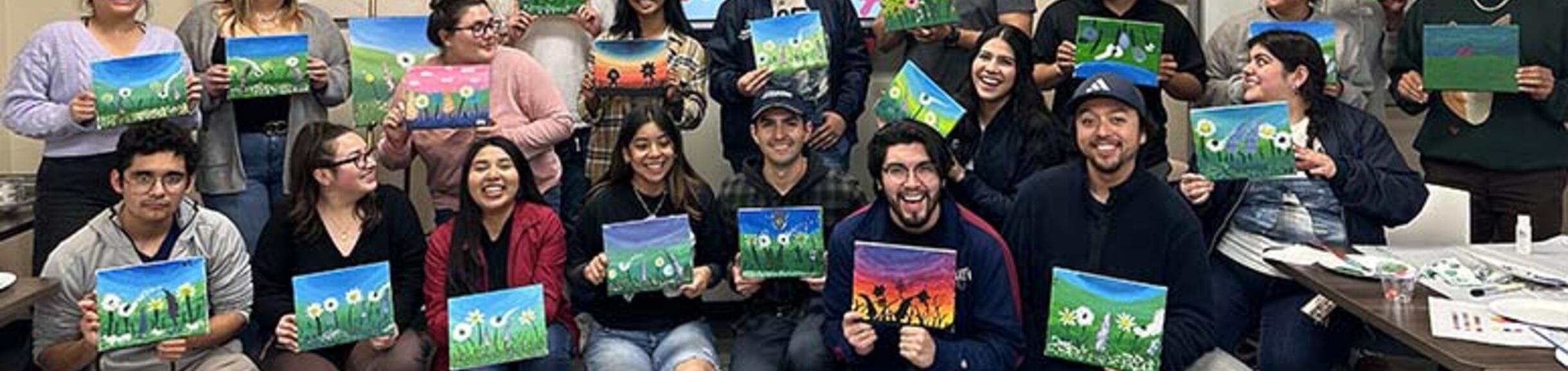 transfer students in the transfer center holding painted canvases