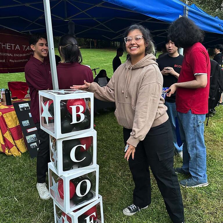 Theta Tau student standing by a BCOE decoration