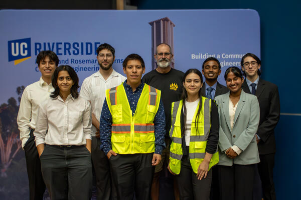 A group of UCR engineering students and a faculty member pose together following a student project presentation, with two students wearing high-visibility safety vests.