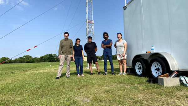 Markus Petters standing in a field with the TRACER research group in Texas with a flux tower in the background.