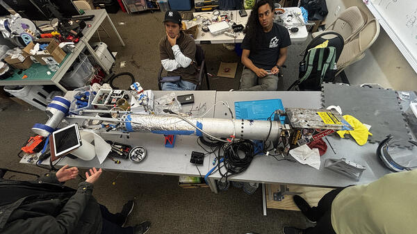Photo of a UCR Highlander Space Program rocket surrounded by students.