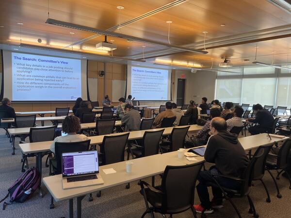 A group of people attending an academic FAME workshop seated in a lecture room facing two screens with presentation slides.