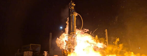 Photo showing the nightime launch of a rocket with flames surrounding the rocket.