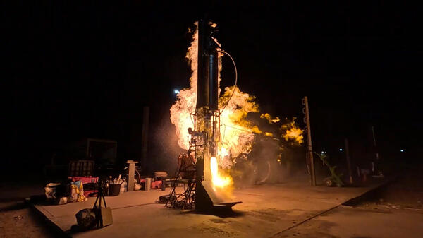 Photo showing the nightime launch of a rocket with flames surrounding the rocket.