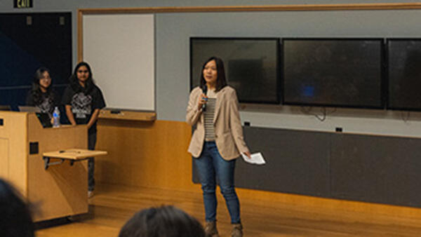 Photo of keynote speaker and BCOE alumni speaking onstage to Rose Hack participants.